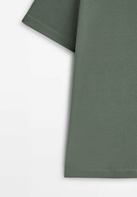T-shirt vert olive à manches courtes, fabriqué en tissu doux. Présente une coupe droite, des coutures délicates et aucun motif ou accent visible.