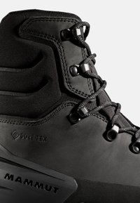 Svart vandringskänga med Gore-Tex-märke, strukturerad ovandel med släta accentdetaljer, metallspännen och en robust gummisula.