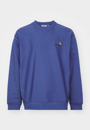 Blue fleece sweatshirt with ribbed cuffs and hem. Features a round neckline and a small embroidered logo on the chest. Soft texture.