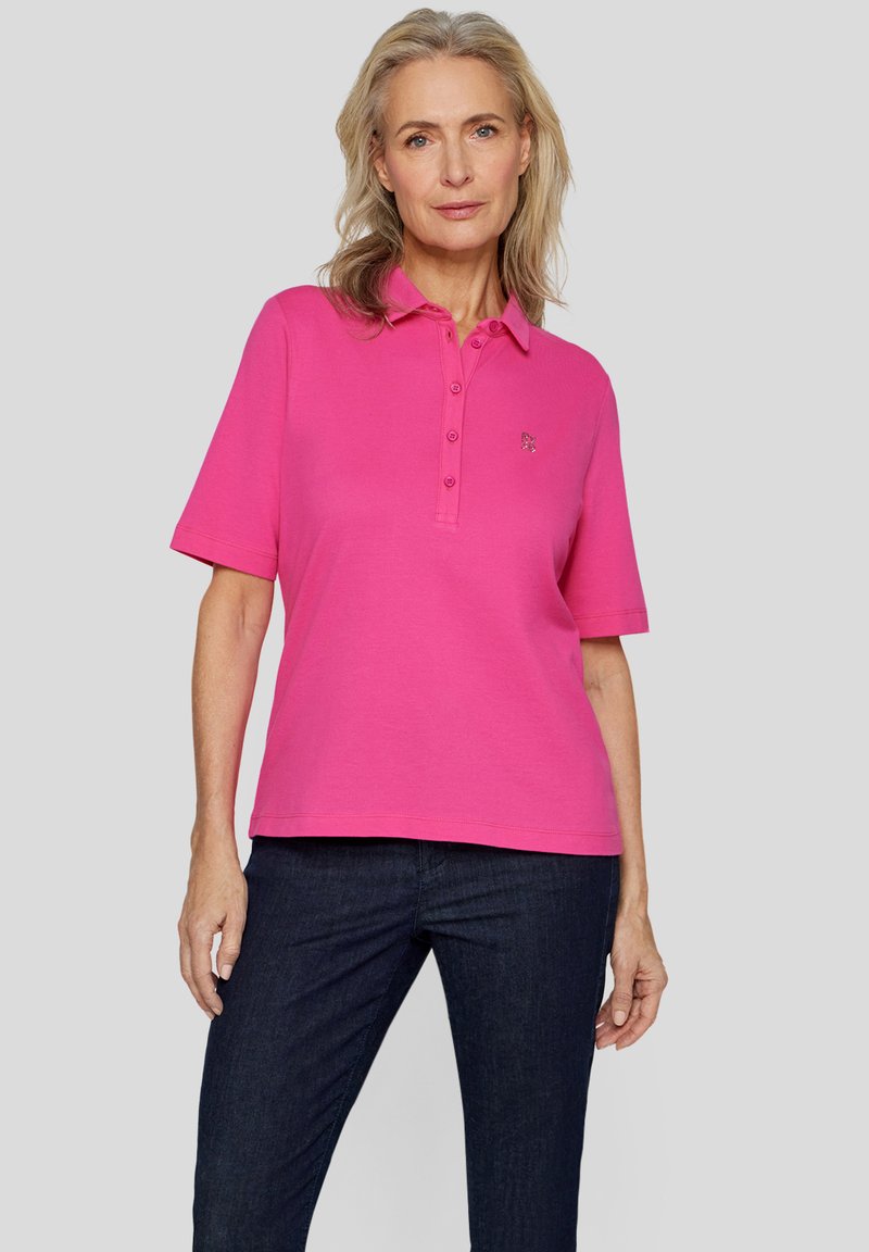 Rosa Poloshirt mit Kragen, kurzen Ärmeln, Knopfleiste mit drei Knöpfen und gesticktem Logo auf der linken Brust. Hergestellt aus weichem Baumwollstoff.
