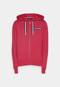 Haut à zip rouge en tissu doux avec une poche avant, des cordons de serrage et un patch logo "HILFIGER" bleu marine sur la poitrine.