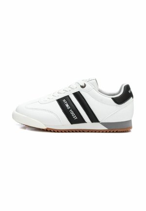 Zapatilla deportiva blanca con rayas negras, diseño con cordones, suela de goma y acento gris en el talón. Textura suave con detalles de costura.