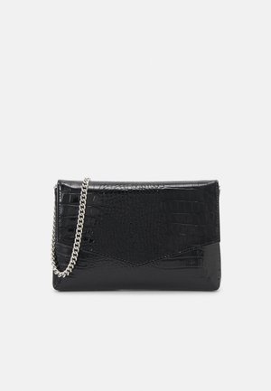 Pochette noire en cuir synthétique imitation crocodile avec bandoulière chaîne argentée et fermeture à rabat style enveloppe sur fond uni.
