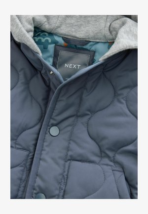 Marine blauwe gewatteerde pufferjack met een grijze capuchon. Voorzien van drukknoopsluitingen, voorkruiszakken en een gestreepte blauwe voering. Het label toont "NEXT."