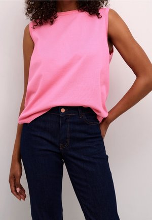 Ärmlös rosa topp med rund halsringning, tillverkad av ett mjukt tyg, i kombination med mörkblå jeans med knäppning och fem fickor.
