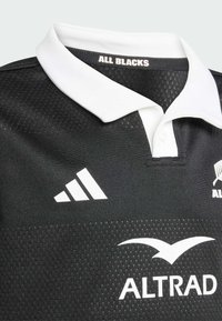 Czarny rugby jersey z białym kołnierzem, z siateczkową teksturą, logo Adidasa i napisem "AL BLACKS" na szyi. Gładki materiał, sportowy krój.