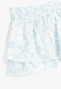 Tejido de flores en tonos azules claros con una cintura fruncida, que presenta dos volantes en capas y un borde blanco con forma de concha en la parte inferior.