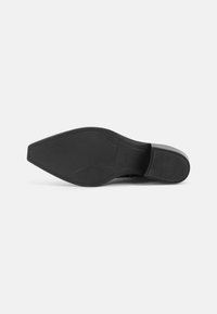 Semelle de chaussure noire avec une surface lisse et plate, présentant une texture subtile le long des bords et un petit talon pour la stabilité.