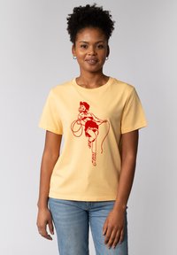 T-shirt en coton jaune avec un imprimé graphique rouge d'une figure avec une corde. Manches courtes et encolure ronde, avec une coupe décontractée.