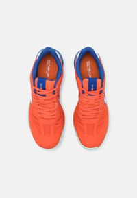 Czerwone siateczkowe sneakersy z niebieskimi akcentami, o okrąłym nosku i teksturowanej podeszwie. Posiadają sznurówki oraz logo na języku.