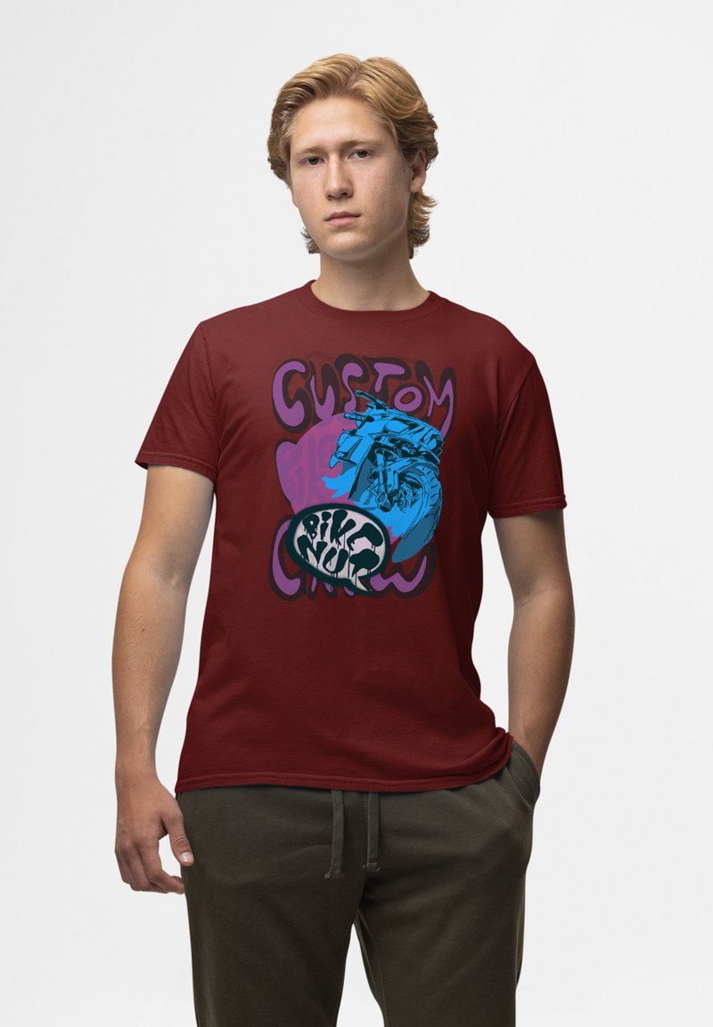 Bordová bavlněná trička s odvážným grafickým designem, na kterém je ilustrace modrého motocyklu a stylizovaný text, umístěné na fialovém pozadí.