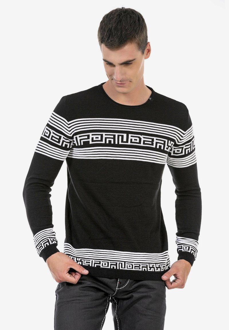 Schwarzer Pullover mit langen Ärmeln, weißem Streifenmuster und geometrischen Akzenten. Gerippte Manschetten und Saum, runder Halsausschnitt. Der Stoff wirkt weich.