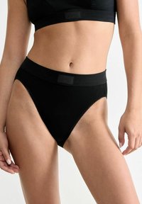 Schwarze hochgeschnittene Unterwäsche aus weichem Stoff, mit einem glatten Bund und dezenten gewellten Kanten, entworfen für Komfort und Passform.