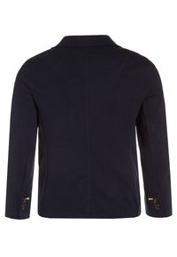 Blazer blu scuro con colletto a rever, tessuto testurizzato, maniche lunghe e polsini con bottone. Presenta una vestibilità su misura e dettagli della cucitura posteriore.