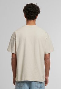 Beige bomulls t-skjorte med avslappet passform, korte ermer og rund hals, med en jevn tekstur og rett nederkant.