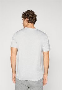 Grå bomuld T-shirt med korte ærmer og rund halsudskæring, set fra ryggen. Har en glat tekstur og afslappet pasform.