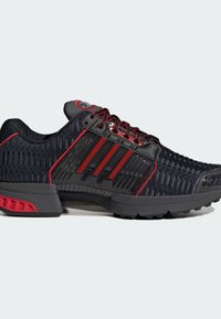 Black athletic shoes with red accents, featuring a mesh upper, three stripes logo, textured pattern, and a cushioned sole for support.