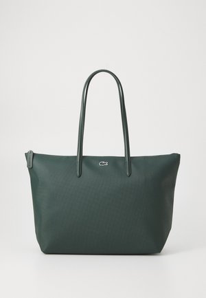 Bolsa tote verde oscuro con asas largas, superficie texturizada, cierre de cremallera y un pequeño logo blanco de cocodrilo en el centro delantero.