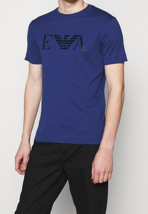 Niebieska bawełniana koszulka z czarnym, stylizowanym logo na piersi. Krótkie rękawy i okrągły dekolt, gładka tekstura, dopasowany krój.