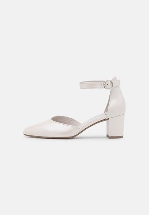 Kvinde sko med lav blokhæl i blank off-white læder med spids tå og justerbar ankelrem med spænde.
