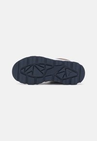 Suela de zapato con una superficie de goma negra texturizada, que presenta profundos surcos y un patrón geométrico para mejorar la tracción.