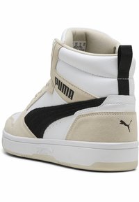 Baskets montantes en cuir blanc et daim beige, avec une bande en daim noir, logo PUMA en noir et doublure texturée.