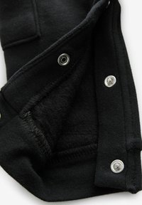 Czarny sweatshirt od wewnątrz z miękkim, polarowym wykończeniem, z metalowymi napami w kolorze srebrnym wzdłuż krawędzi oraz przeszytym dołem.