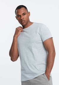 Grå kortærmet t-shirt i en meleret tekstur med rund hals, der har flade sømme og en almindelig pasform. Kombineret med lysegrå shorts.