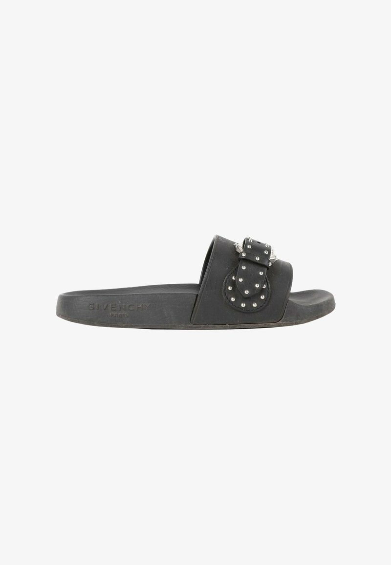 Sandale slide noire Givenchy avec une boucle de bride décorative cloutée sur une semelle plate, vue de profil sur fond blanc.