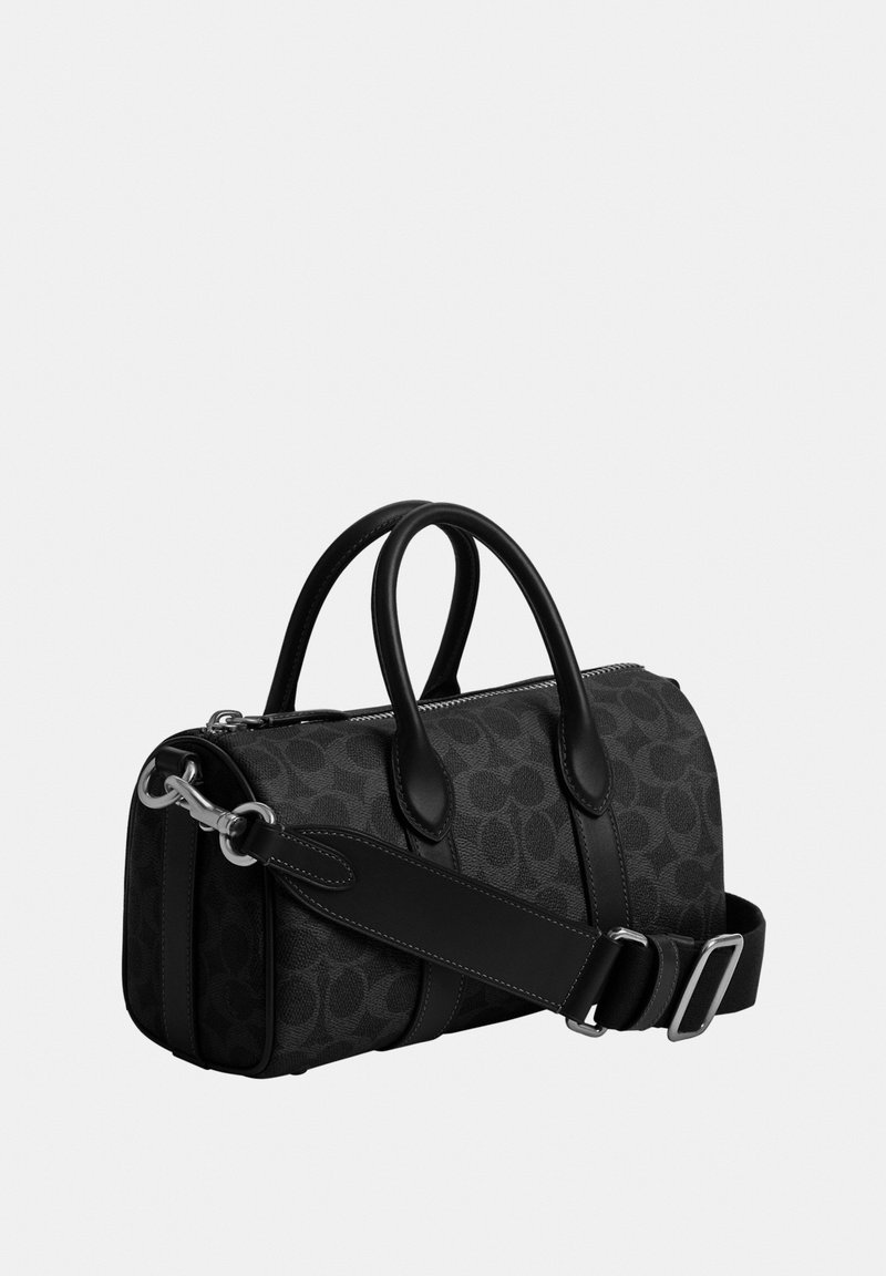 Sac à main cylindrique noir à motifs avec deux poignées, bandoulière amovible et ferrures argentées sur un fond clair uni.