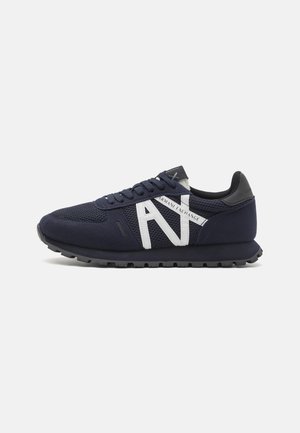 Zapatilla azul marino con detalles de malla y ante, logo blanco "AX Armani Exchange" en el lateral, cuello acolchado negro y suela de goma texturizada.