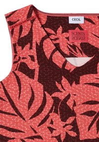 Haut corail sans manches avec un motif floral tropical marron foncé et des étiquettes de marque visibles portant les noms Cecil et Scents of Salt & Fresh Pine.
