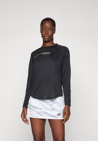 Zwarte lange mouwen sportshirt met een ronde halslijn en zilveren logo, gecombineerd met een witte rok met een lichtblauw abstract patroon.