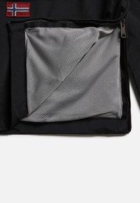 Czarna kurtka z zasuwaną siateczkową kieszenią wewnętrzną oraz małą naszywką z flagą Norwegii przyszytą nad kieszenią po lewej stronie.