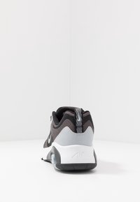 Černá a šedá sportovní bota s texturovaným látkovým svrškem, polstrovaným límcem a bílou stélkou s viditelnou vzduchovou jednotkou.