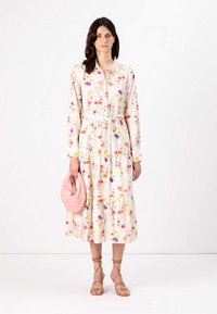 Rochie cu mânecă lungă, cu nasturi, cu un model floral în culori pastelate, talie strânsă, fustă în straturi, asortată cu o geantă roz.