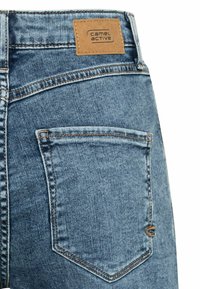 Lichtblauwe denimjeans met een gestructureerde afwerking. Kenmerken zijn een tan merkpatch, contrasterende stiksels en een achterzak met een gebogen ontwerp.