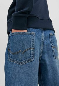 Jeans i denim med en medelhavblå tvätt och två bakfickor med sömdetaljer. Tyget har en texturerad look och en avslappnad passform.