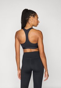 Μαύρο αθλητικό τοπ με σχέδιο racerback και εφαρμοστό ζωνάρι στη μέση, σε συνδυασμό με μαύρο κολάν ψηλόμεσο, με λεία υφή.