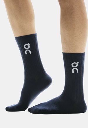Marineblaue Crew-Socken mit gerippter Textur und weißem Logo. Eng anliegendes Design mit verstärktem Fersen- und Zehenbereich für Haltbarkeit.