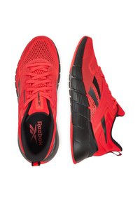Scarpe sportive rosse con tomaia in rete, dettagli neri, suola nera imbottita e marchio ben visibile sulla linguetta e sui lati.