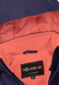 Navy blå jakkeinnside med rosa fleecefôr og logoetikett. Har opphengsløkke og glatt stoffstruktur. Glidelås lukking.