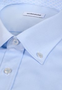 Lichtblauw, gestructureerd overhemd met een button-down kraag en witte knopen, met het label "seidensticker" aan de binnenkant van de kraag.