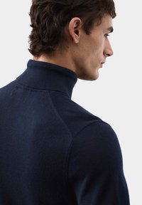 Námořnicky modrý rolák s měkkou texturu, přiléhavým střihem a žebrovaným límcem. Obsahuje švy na ramenou a na zádech.