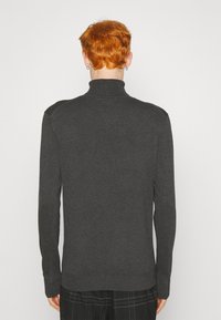 Suéter de cuello alto en gris oscuro con mangas largas, puños y dobladillo acanalados. Textura suave, diseño ajustado, detalles mínimos y sin patrones visibles.