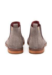 Stivaletti alla caviglia in suede grigio con suola in pelle marrone, pannelli laterali elastici e interno rosso a contrasto. Presentano un inserto per il trascinamento sul retro.