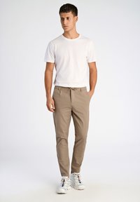 Beige chino's met zijzakken, een trekkoord in de taille en een tapered snit, gecombineerd met een slim-fit wit T-shirt en stevige witte sneakers.