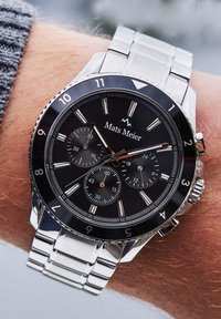 Silberne Metalluhr mit schwarzem Zifferblatt, Chronographenfunktionen, silbernen Akzenten und einem Armband aus rostfreiem Stahl. Markenname: Mats Meier.