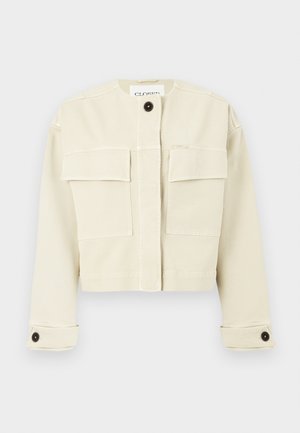 Cream-colored cropped jacket with round collar, two large front flap pockets, buttoned cuffs, and a single black button at the neck.