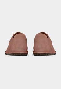 Ζευγάρι ροζ σουέντ παπούτσια τύπου slip-on, που φαίνονται από πίσω, με λείες φτέρνες και σκούρες καουτσούκ σόλες σε λευκό φόντο.